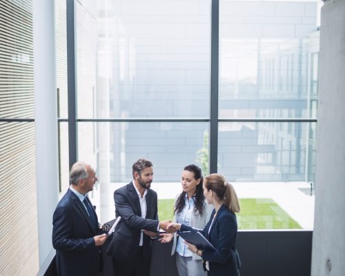 Group of businesspeople having a discussion near staircase in office